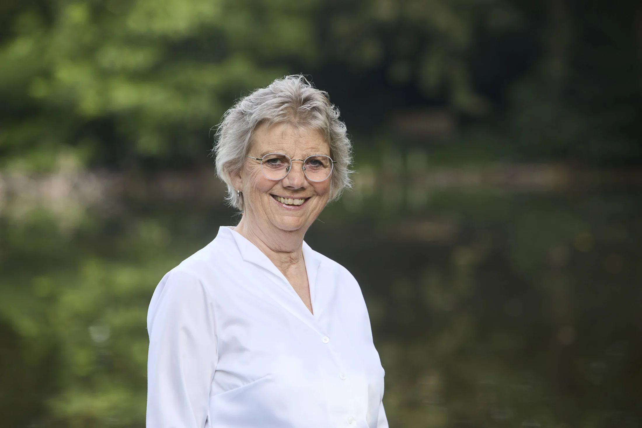 Claudia lächelt vor einem grünen, unscharfen Hintergrund